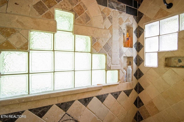 bathroom with a tile shower and a wealth of natural light