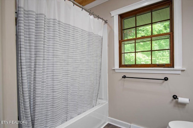 full bathroom featuring shower / bath combo, baseboards, and toilet