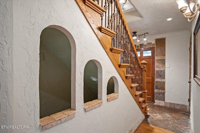 interior space featuring stone finish flooring, a textured ceiling, and a textured wall