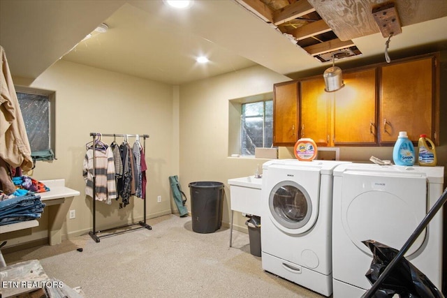 laundry area featuring light colored carpet, washing machine and clothes dryer, cabinet space, and baseboards