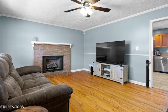 living room featuring a textured ceiling, ceiling fan, baseboards, light wood finished floors, and crown molding