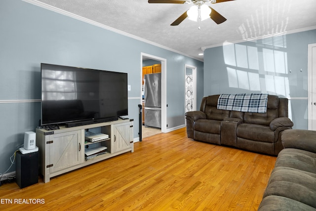 living room featuring baseboards, a ceiling fan, light wood-style flooring, crown molding, and a textured ceiling