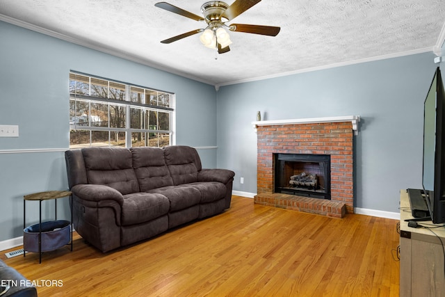 living area with a textured ceiling, baseboards, light wood-style flooring, and crown molding