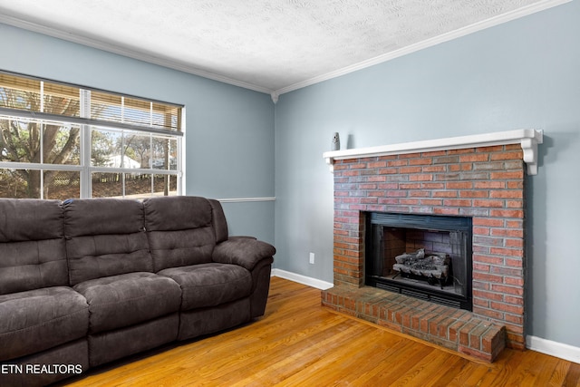 living area featuring a fireplace, ornamental molding, a textured ceiling, wood finished floors, and baseboards