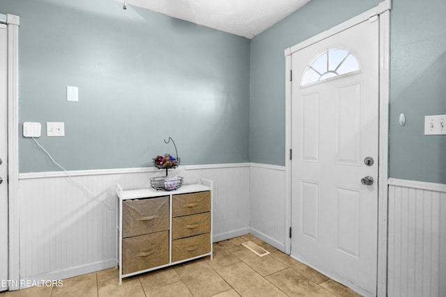 entrance foyer with a wainscoted wall and light tile patterned floors