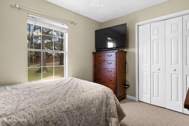 bedroom featuring baseboards, a closet, and light colored carpet