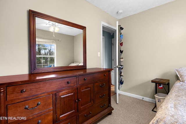 bedroom with baseboards, a textured ceiling, and light colored carpet