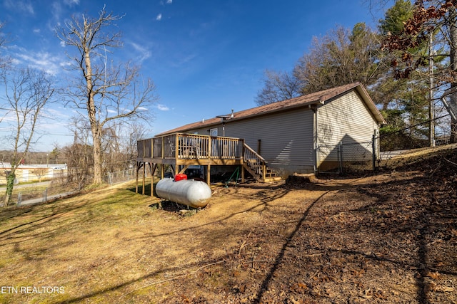 back of property with a yard, fence, a wooden deck, and stairs