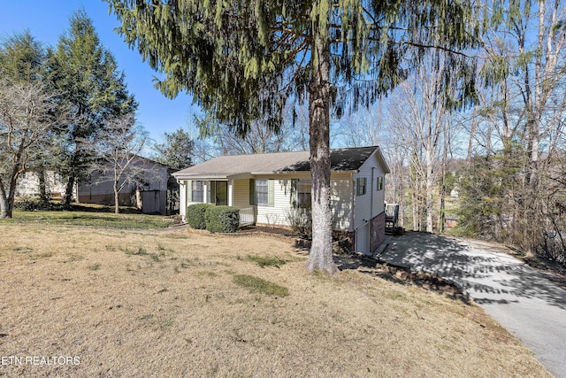 ranch-style house featuring driveway and a front lawn