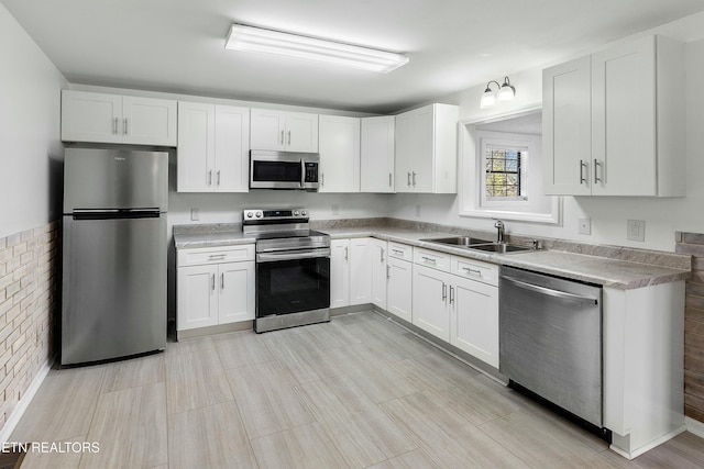 kitchen with white cabinetry, stainless steel appliances, a sink, and light countertops