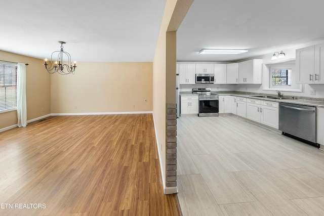 kitchen featuring light wood-style floors, white cabinetry, stainless steel appliances, and a sink