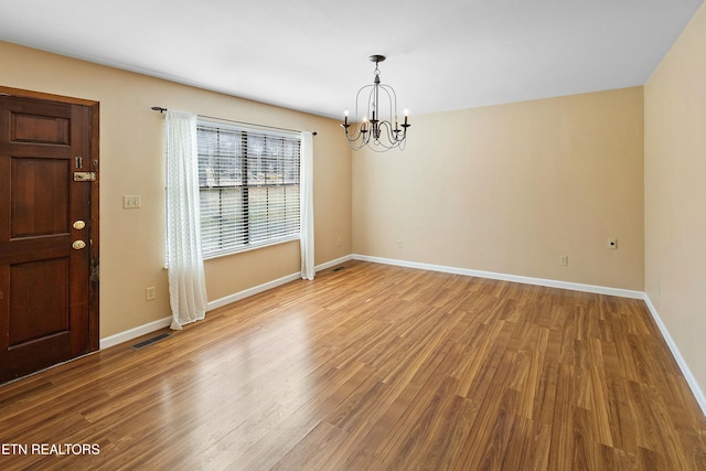 interior space featuring baseboards, visible vents, a chandelier, and wood finished floors