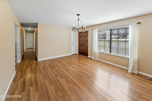 unfurnished dining area with baseboards, a chandelier, and wood finished floors