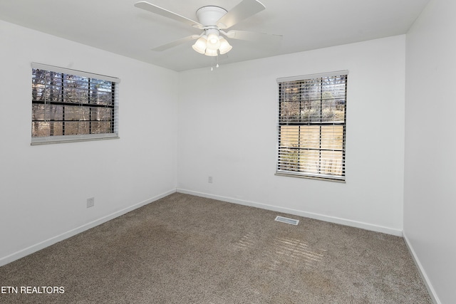 carpeted empty room featuring ceiling fan, visible vents, and baseboards