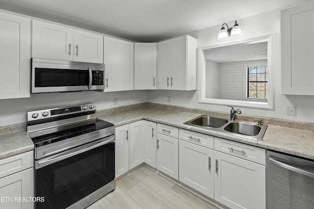 kitchen with appliances with stainless steel finishes, white cabinets, and a sink