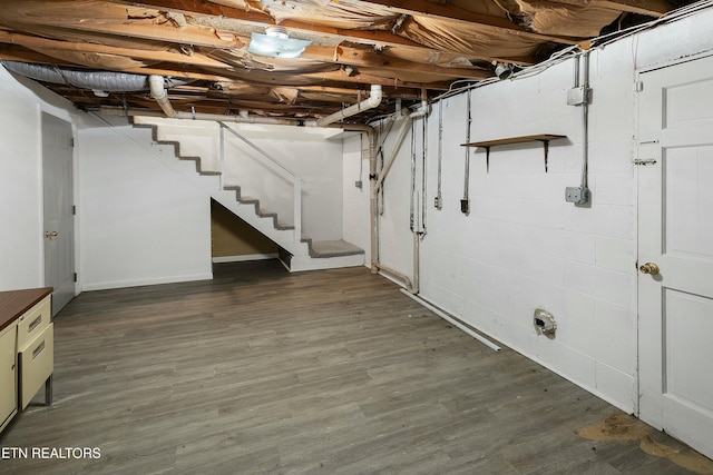 unfinished basement featuring stairs and wood finished floors