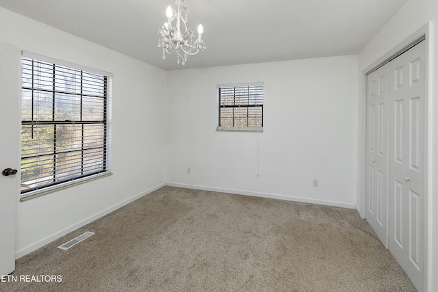 unfurnished bedroom featuring multiple windows, carpet floors, a closet, and visible vents