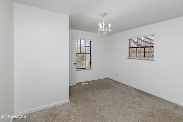 empty room with carpet floors, a chandelier, and baseboards