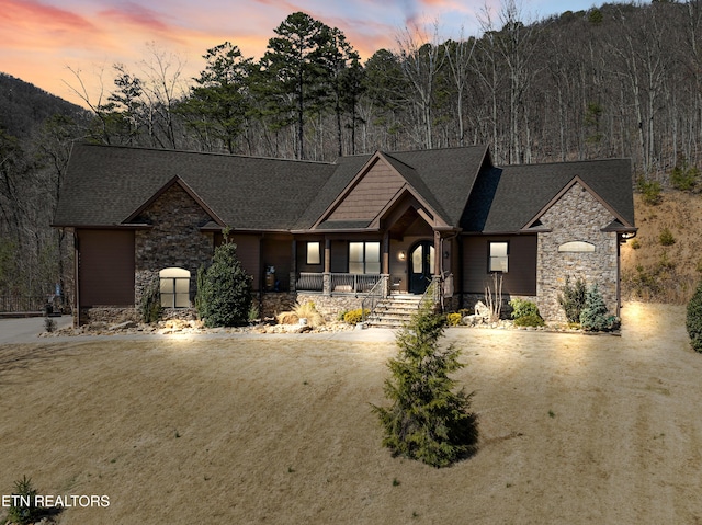 craftsman inspired home with driveway, stone siding, and a porch