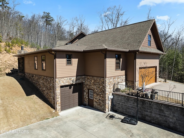 view of front of house featuring a garage, concrete driveway, and roof with shingles