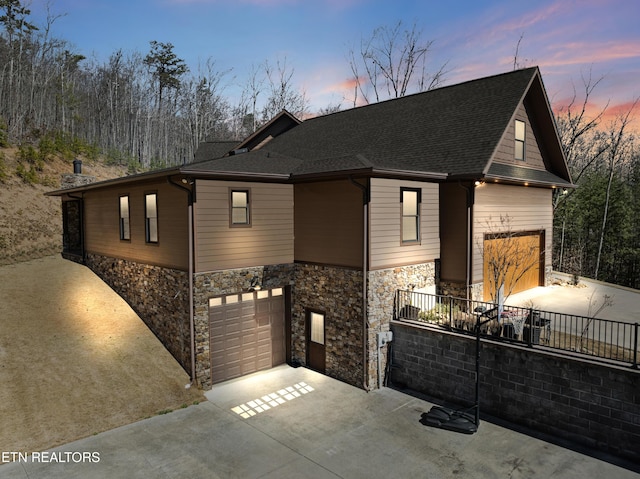 view of front of home with a garage, roof with shingles, and driveway