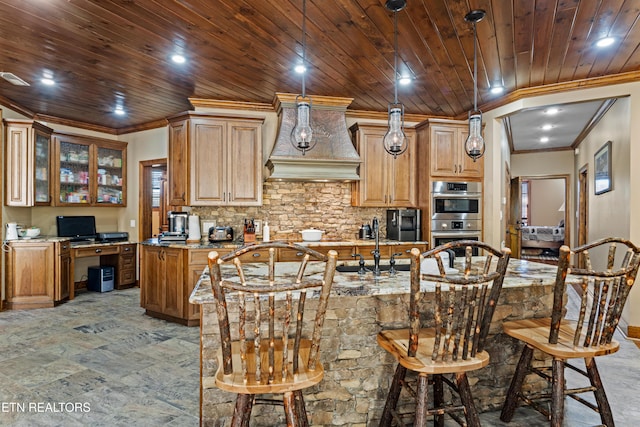 kitchen with a center island with sink, wood ceiling, ornamental molding, double oven, and backsplash