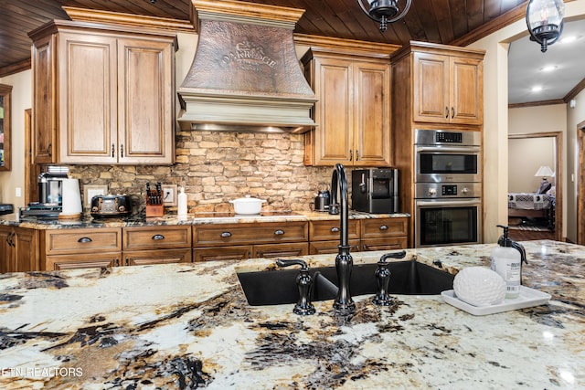 kitchen featuring premium range hood, decorative backsplash, light stone counters, and crown molding