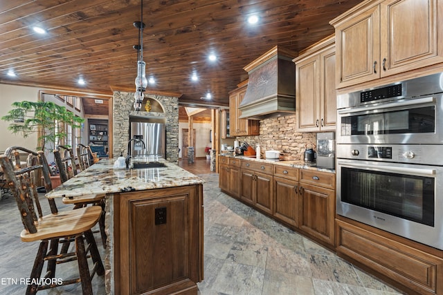 kitchen featuring stainless steel appliances, premium range hood, a sink, and wood ceiling