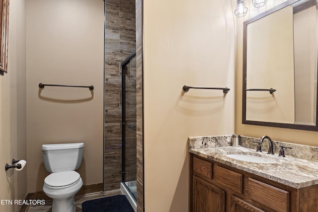 full bathroom with toilet, a shower stall, baseboards, and vanity