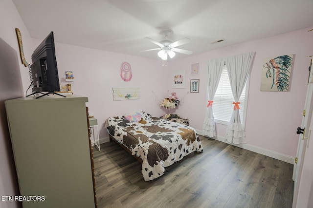 bedroom with a ceiling fan, visible vents, baseboards, and wood finished floors