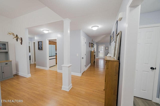 hallway with baseboards, light wood-style flooring, and ornate columns