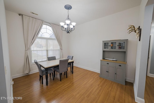 dining space with visible vents, light wood-style flooring, baseboards, and an inviting chandelier