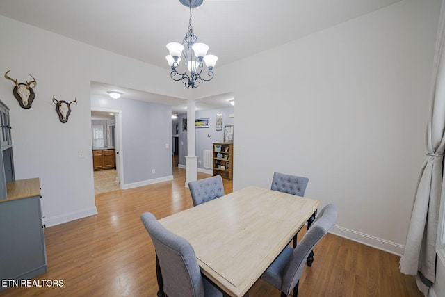 dining room featuring a chandelier, light wood-style flooring, and baseboards