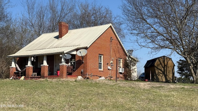 exterior space featuring brick siding, a front lawn, a shed, a chimney, and an outdoor structure