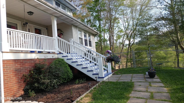 view of property exterior featuring covered porch, fence, and stairs