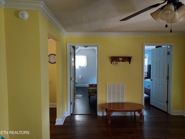 hall featuring a textured ceiling, ornamental molding, wood finished floors, and visible vents