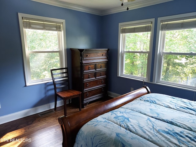 bedroom featuring baseboards, multiple windows, wood finished floors, and crown molding