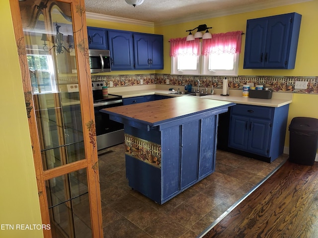 kitchen with blue cabinets, butcher block countertops, a sink, appliances with stainless steel finishes, and crown molding