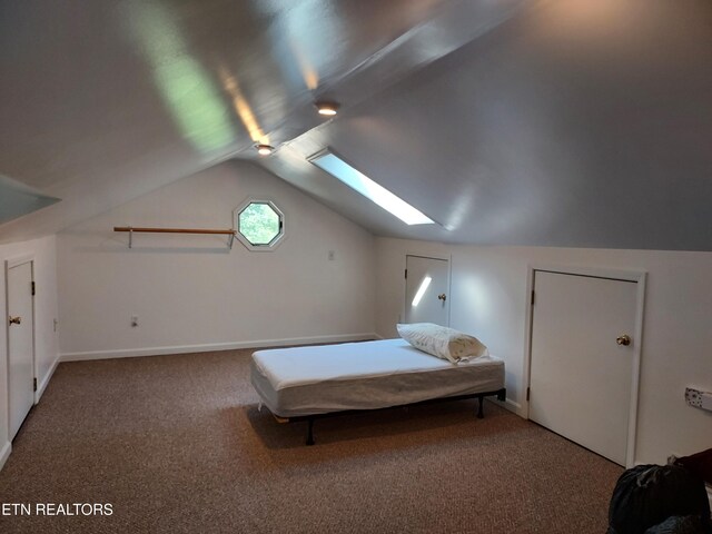 bedroom with vaulted ceiling with skylight, carpet, and baseboards