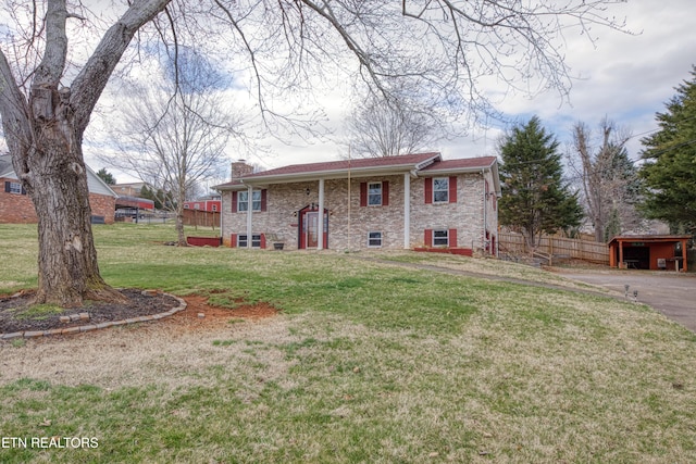 split foyer home with a front lawn, a chimney, fence, and brick siding