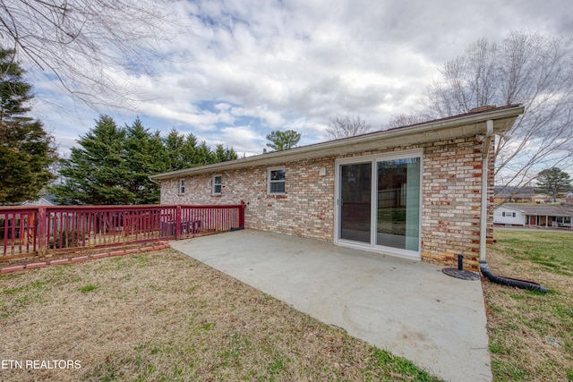 back of property featuring a yard, brick siding, and a patio area