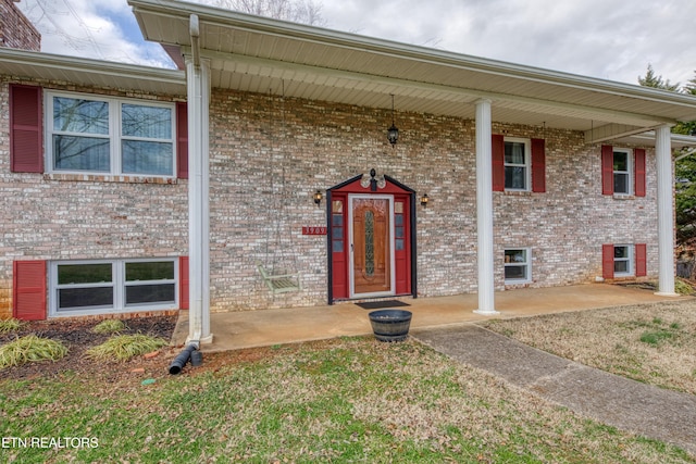 view of exterior entry with covered porch and brick siding