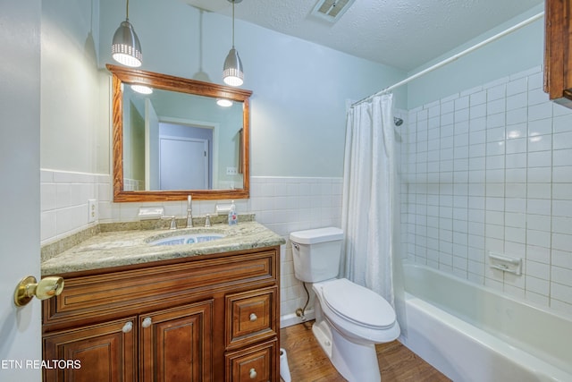 full bathroom with visible vents, toilet, wood finished floors, a textured ceiling, and tile walls