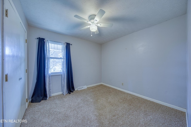 empty room with a textured ceiling, carpet, visible vents, and a ceiling fan