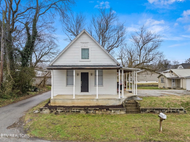 view of front of home with driveway, a porch, and a front lawn