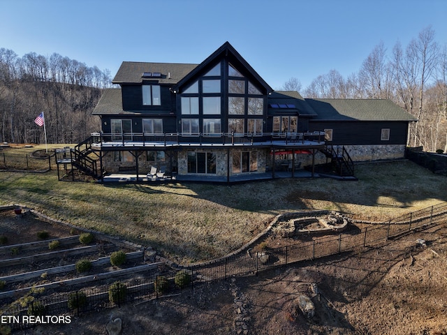 rear view of house with stone siding, a lawn, a deck, and stairs