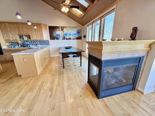 interior space with decorative backsplash, high vaulted ceiling, light wood-type flooring, a peninsula, and a tile fireplace