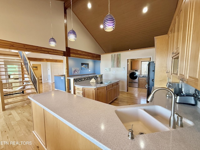 kitchen featuring black appliances, washer / clothes dryer, a sink, and light wood-style floors