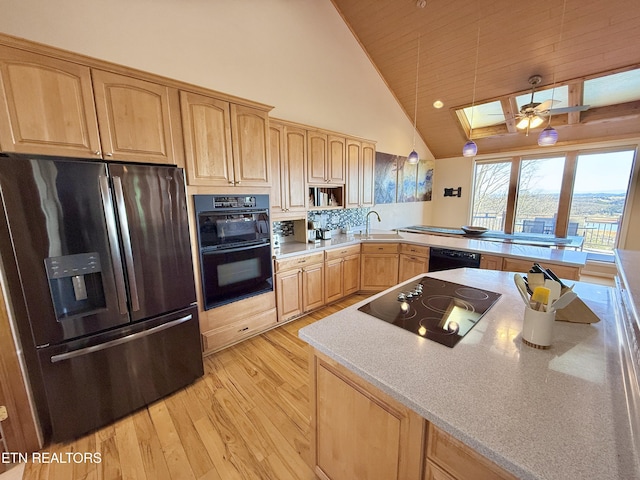 kitchen featuring black appliances, light brown cabinetry, and a sink