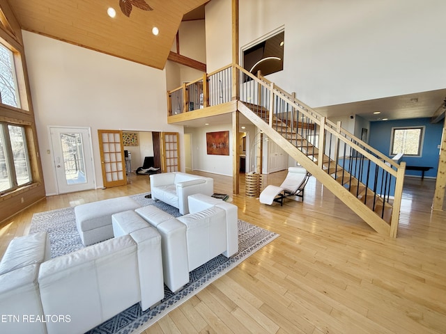 living area featuring high vaulted ceiling, hardwood / wood-style floors, stairway, and a healthy amount of sunlight